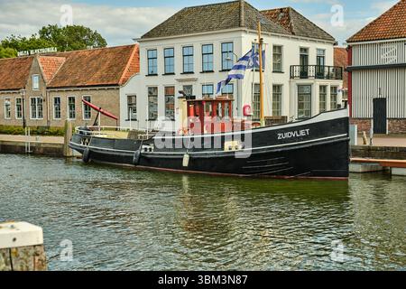 26. Mai 2025: Zierikzee-Niederlande: Ein traditionelles schwarz-gelbes Schlepper Zuidvliet mit seeländischer Flagge, das entlang des Kais vor dem Histori vertäut Stockfoto