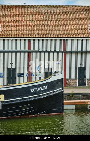 26. Mai 2025: Zierikzee-Niederlande: Ein traditioneller schwarz-gelber Schlepper-Bug mit geuzener Flagge, der entlang des Kais vor den historischen Stads vertäut Stockfoto