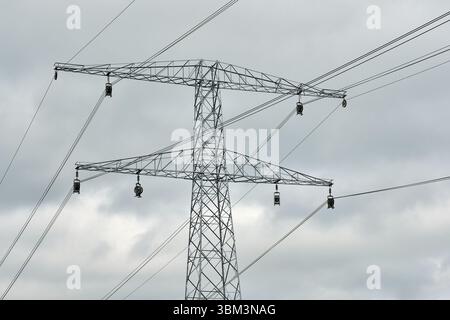 Stahlgetriebeturm mit sichtbaren Riemenscheiben, da neue Hochspannungskabel unter bewölktem Himmel installiert werden. Stockfoto