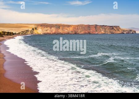 Ein atemberaubender Blick auf Playa Roja, bekannt für seinen einzigartigen roten Sand und die dramatischen Klippen im Paracas Natural Reserve. Stockfoto