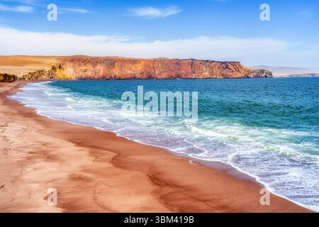 Ein atemberaubender Blick auf Playa Roja, bekannt für seinen einzigartigen roten Sand und die dramatischen Klippen im Paracas Natural Reserve. Stockfoto