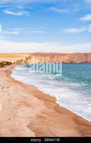 Ein atemberaubender Blick auf Playa Roja, bekannt für seinen einzigartigen roten Sand und die dramatischen Klippen im Paracas Natural Reserve. Stockfoto
