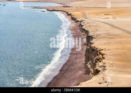 Ein atemberaubender Blick auf Playa Roja, bekannt für seinen einzigartigen roten Sand und die dramatischen Klippen im Paracas Natural Reserve. Stockfoto