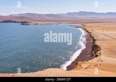 Ein atemberaubender Blick auf Playa Roja, bekannt für seinen einzigartigen roten Sand und die dramatischen Klippen im Paracas Natural Reserve. Stockfoto