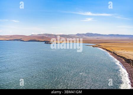 Ein atemberaubender Blick auf Playa Roja, bekannt für seinen einzigartigen roten Sand und die dramatischen Klippen im Paracas Natural Reserve. Stockfoto