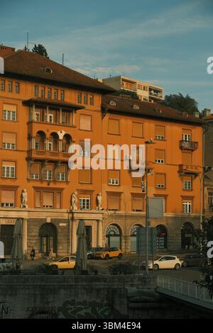 Dieses markante orangene Gebäude, das in das goldene Licht des späten Nachmittagslichts getaucht ist, steht stolz an einer europäischen Straße. Stockfoto