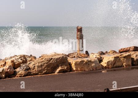 Eine felsige Küste mit einem großen Felsen in der Mitte. Das Wasser ist rau und die Wellen brechen gegen die Felsen Stockfoto