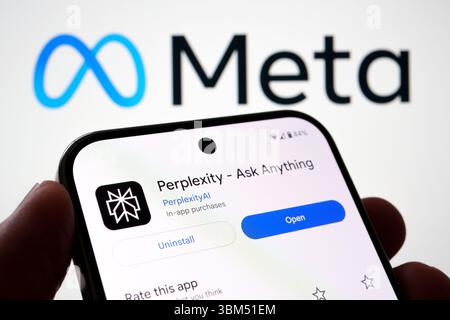 Der Bildschirm der Perplexity-KI-Software wird in der Hand gehalten, hinter dem Meta-Firmenlogo. Stafford, Großbritannien, 24. Juni 2025 Stockfoto