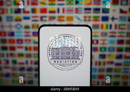 SHANGHAI, CHINA - 25. JUNI 2025 - das Logo der INTERNATIONALEN ORGANISATION FÜR MEDIATION auf einem Smartphone mit den Nationalflaggen verschiedener Länder auf der ganzen Welt im Hintergrund in Shanghai, China am 25. Juni 2025. Stockfoto