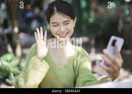 Schöne zuversichtliche asiatische junge Frau verwenden Smartphone-College-Handy-Süchtige verbringen Zeit mit Nachrichten Technologie E-Commerce-Konzept Stockfoto