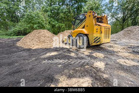 Kompaktlader-Bagger bei Bauarbeiten. Minilader bewegt die Erde auf der Baustelle. Stockfoto