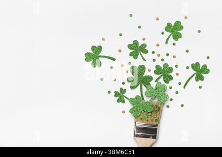 Kreatives St. Patricks Day-Konzept. Pinsel mit grünem Glitzerschamrock und Konfetti. Minimaler St. Patricks Day Hintergrund Stockfoto