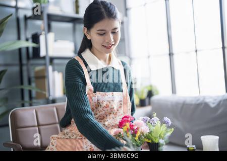 Glückliche asiatische Frau, die Blumen arrangiert, um das Grün zu pflegen Stockfoto