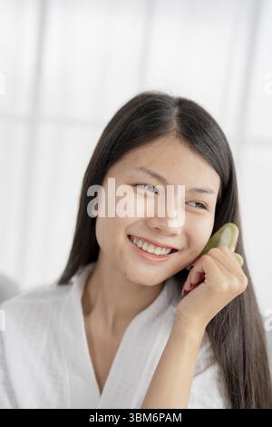 Tägliche Schönheit Routine Asiatische Frau Selbstpflege Gua Sha Gesichtsmassage traditionelle Medizin Gua Sha Quarzstein Kosmetik natürliche Trend Stockfoto
