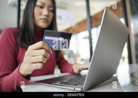 Frau, die auf Laptop mit Kreditkarte für Internet Online-E-Commerce-Einkaufen Geld ausgeben Online-Einkaufen Mobiltelefon Laptop-Technologie CON Stockfoto