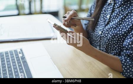 Asiatische Frau, die Smartphone-Mobilsüchtige verwendet, die Zeit mit Nachrichten Social Media Handy Technologie E-Commerce Konzept verbringt Stockfoto
