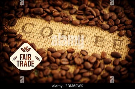 Die flache Abbildung zeigt geröstete Kaffeebohnen auf grobem Sackleinen mit Fair Trade-Label Stockfoto