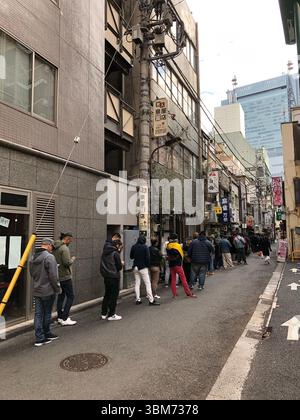 Tokio, Japan 01.01.2020 Shimbashi Japaner und Touristen stehen in einem Restaurant in der Schlange. Hochwertiges Foto, vertikales Foto Stockfoto