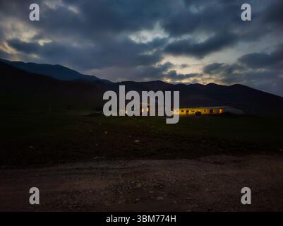 Beleuchtete Bauernhäuser in heiterer ländlicher Bergnacht in Kirgisistan Stockfoto