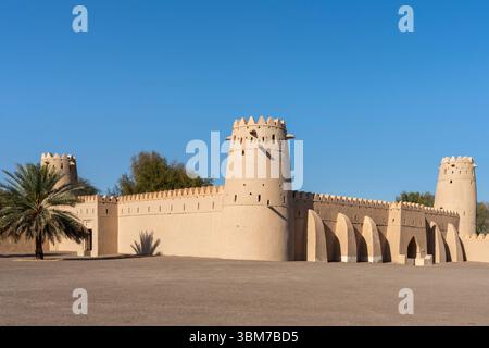 Ein großer Blick auf eine Festung mit zinnenbesetzten Mauern und Türmen steht im Sonnenlicht am Al Jahili Fort in Al Ain Vereinigte Arabische Emirate. Stockfoto