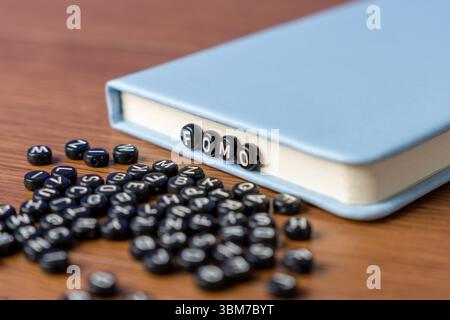 Buchstabenperlen mit der Schreibweise „FOMO“ mit mehr verstreuten Perlen auf einem Holztisch. Angst vor dem Verpassen, soziale Angst und psychische Gesundheitskonzepte. Stockfoto