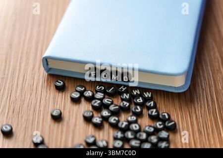 Buchstabenperlen mit der Schreibweise „FOMO“ mit mehr verstreuten Perlen auf einem Holztisch. Angst vor dem Verpassen, soziale Angst und psychische Gesundheitskonzepte. Stockfoto