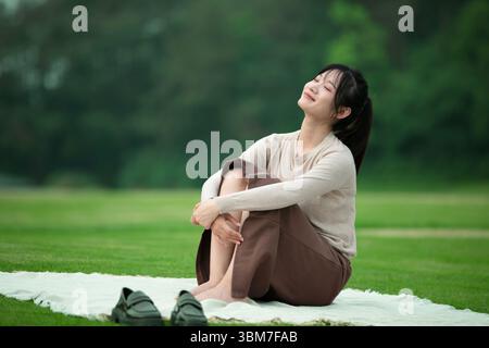 Eine junge Chinesin, die auf einem mat​ im Freien ruht Stockfoto
