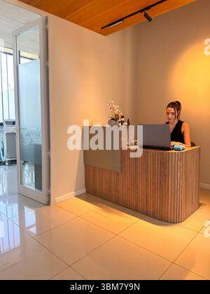Junge Frau in einem modernen Empfangsbereich k, die in einer laptop.in Klinik, einem Spa, Schönheitssalon, Wellness-Klinik oder ähnlichen serviceorientierten Räumen arbeitet Stockfoto