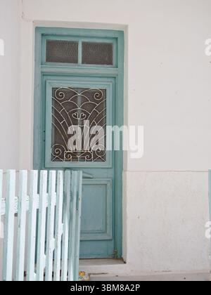 Verwitterte hellblaue Holztür und Tor an einer weiß getünchten griechischen Hausfassade, typische Architektur der Kykladen. Stockfoto