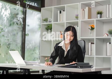 Wirtschaft und Finanzen. Junge Frau, die Dokumente und Planungen in einem modernen Büro überprüft. Stockfoto