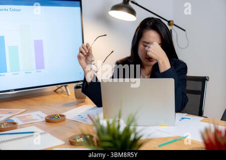 Erschöpfte Büroangestellte, die nach später Arbeit am Computer Augenmüdigkeit empfindet. Stockfoto