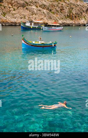 Mediterraner Urlaub, Blick auf eine Frau, die im klaren blauen Mittelmeer schnorchelt in der Xlendi Bay auf der Insel Gozo, Malta. Stockfoto