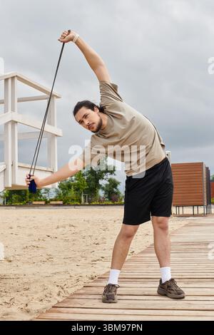Ein junger Mann führt im Freien ein dehnendes Workout durch und zeigt dabei sein Engagement und seine Anstrengung. Stockfoto