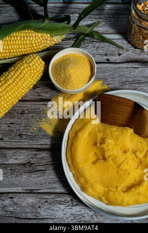 Köstliche Polenta mit Maiskolben und Mehl auf rustikalem Holztisch Stockfoto
