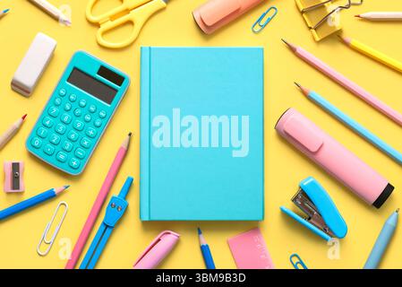 Draufsicht des blauen Notizblocks und der Schulmaterialien mit Platz für Text auf gelbem Hintergrund. Back-to-School-Konzept Stockfoto