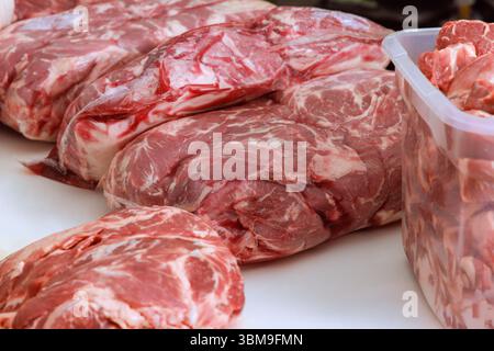 Auf dem Tisch werden verschiedene Stücke von rohem Fleisch präsentiert, die die Frische der Käufer auf dem Markt zeigen. Stockfoto