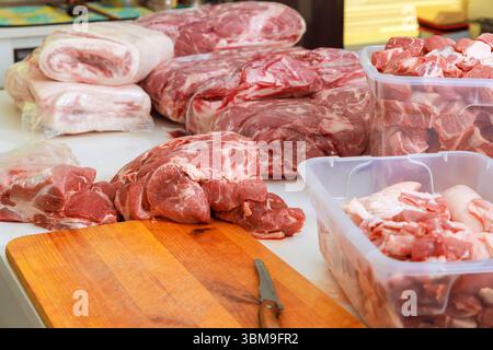 In der Metzgerei werden verschiedene Schweinefleischstücke auf Holzoberfläche angeordnet, die die Zubereitung frischer Produkte hervorheben. Stockfoto