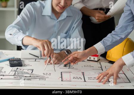 Zusammenarbeit und Architekturplanung. Zwei Fachleute arbeiten an der Erstellung von Entwurfsplänen mit Materialien und Werkzeugen zusammen. Stockfoto