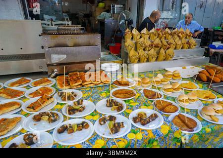 Dieses Bild fängt einen lebendigen und geschmackvollen Moment auf dem Markt von Ballarò in Palermo, Sizilien, ein. Ein farbenfroher Tisch ist mit traditionellen sizilianischen Straßen gefüllt Stockfoto