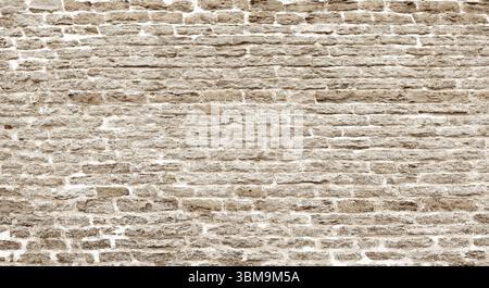 Nahaufnahme einer alten beigefarbenen Ziegelwand, die einen rustikalen und strukturierten Hintergrund schafft, ideal für Designprojekte Stockfoto