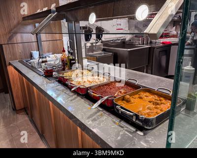 Buffettisch mit mehreren scheuernden Gerichten gefüllt mit warmen Speisen wie Pasta, Reis, Fleischsoße und Fleischbällchen in einem Restaurant oder einer Cafeteria. Stockfoto