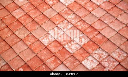 Nahaufnahme von sich überlagernden roten Lehm-Dachziegeln, die ein strukturiertes geometrisches Muster bilden Stockfoto