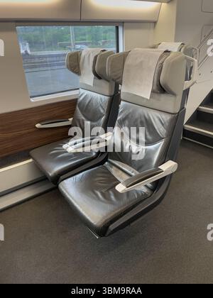 Leere Ledersitze erwarten die Passagiere in einem modernen Hochgeschwindigkeitszug, der Komfort und Stil für eine entspannte Reise bietet Stockfoto