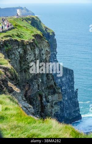 Cliffs of Moher sind dramatische Küstenklippen, die den Atlantischen Ozean in Irland treffen. Mit O'Brien's Tower und Besuchern, die den Weg entlang laufen. Stockfoto