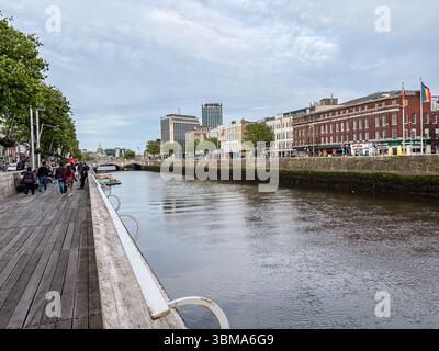Fluss Liffey. Blick auf die Promenade des River Liffey in Dublin, Irland, mit Gebäuden und Menschen, die entlang des Flusses spazieren. Stockfoto