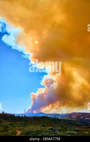 Rauchwolke Aus Wildfeuer, Die Über Dem Bergwald Unter Dem Sonnigen Himmel Aufsteigt Stockfoto