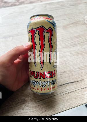 Kiew, Ukraine - 24. Juni 2025: Person, die eine Energie-Getränkedose Monster Punch vor einem natürlichen hölzernen Hintergrund hält Stockfoto
