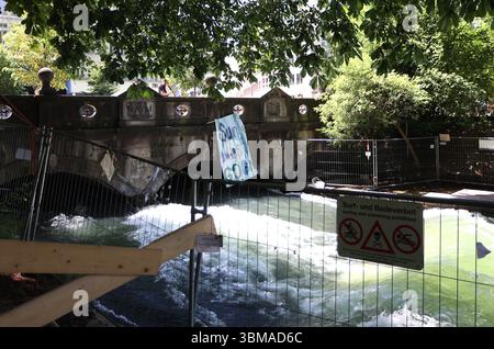 Ein Sommertag in der Landeshauptstadt München. Hier der Blick an der Eisbachwelle auf ein Absperrgitter mit einem Hinweisschild, Surf und Badeverbot und ein Banner Surf muss weitergehen *** Ein Sommertag in der Landeshauptstadt München hier ist der Blick auf die Eisbachwelle auf eine Barriere mit einem Schild zum Surfen und Schwimmen und einem Banner Surf muss weitergehen Stockfoto