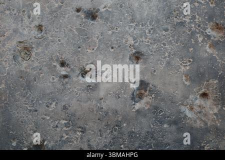 Eine abstrakte Nahaufnahme einer grauen Oberfläche, die stark vernarbt ist mit Schuss- und Schrapnelllöchern aus dem Zweiten Weltkrieg in Berlin. Stockfoto