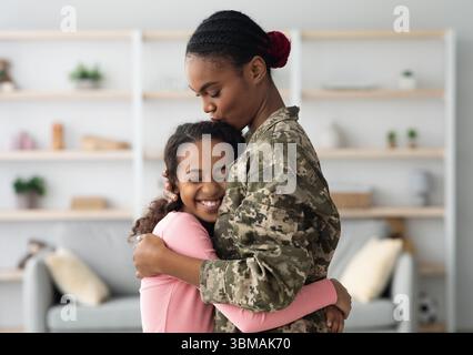 Seitenansicht der schwarzen Mutter in Militäruniform umarmende Kind Stockfoto